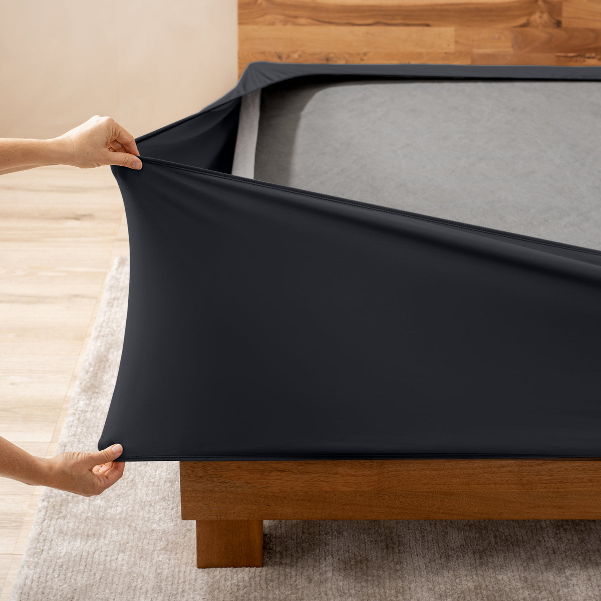 A person stretching a box spring cover