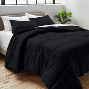 Comforter on a bed with white pillows and a plant in the corner.