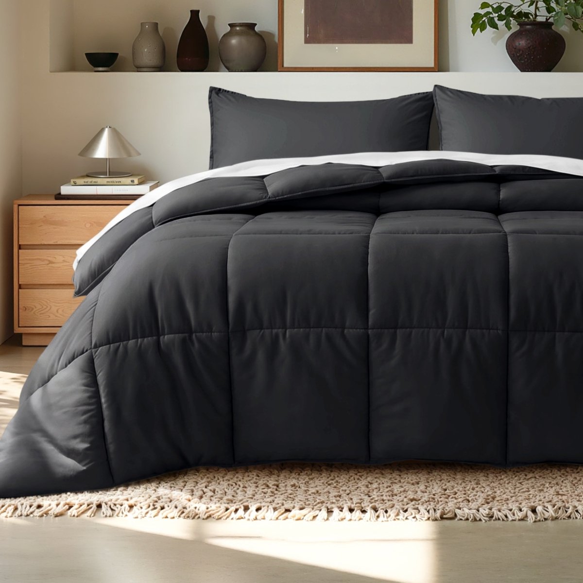 Comforter on a bed in a bedroom setting with a wooden nightstand and decorative items.