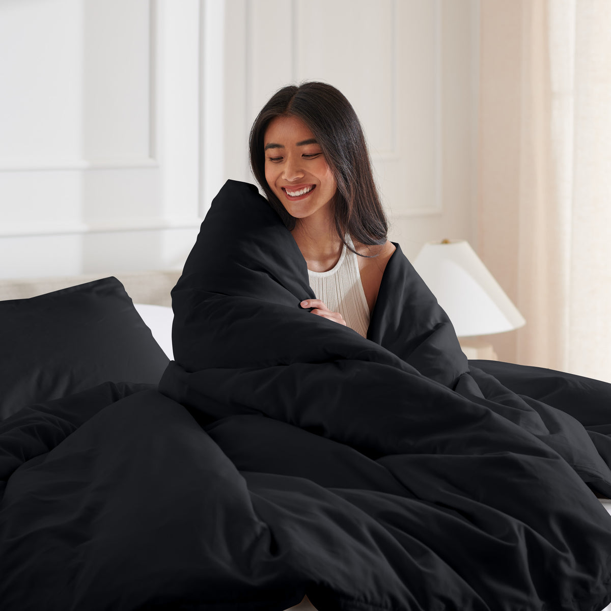 Woman smiling under duvet cover set in a bedroom setting