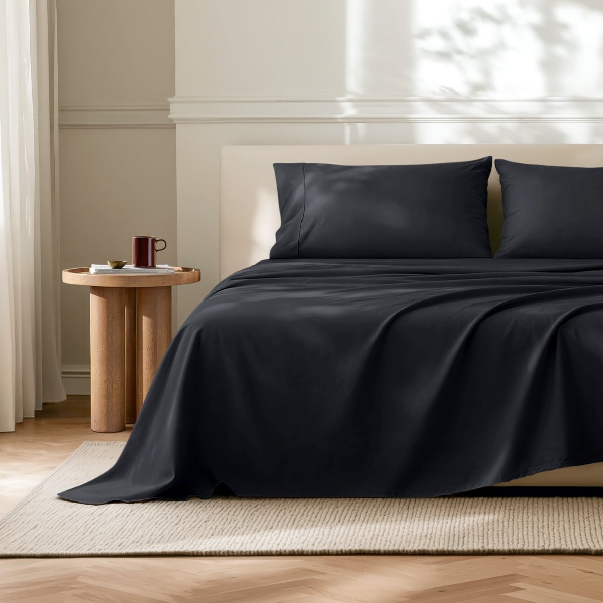 Microfiber flat sheet on a bed in a bedroom with a wooden side table.