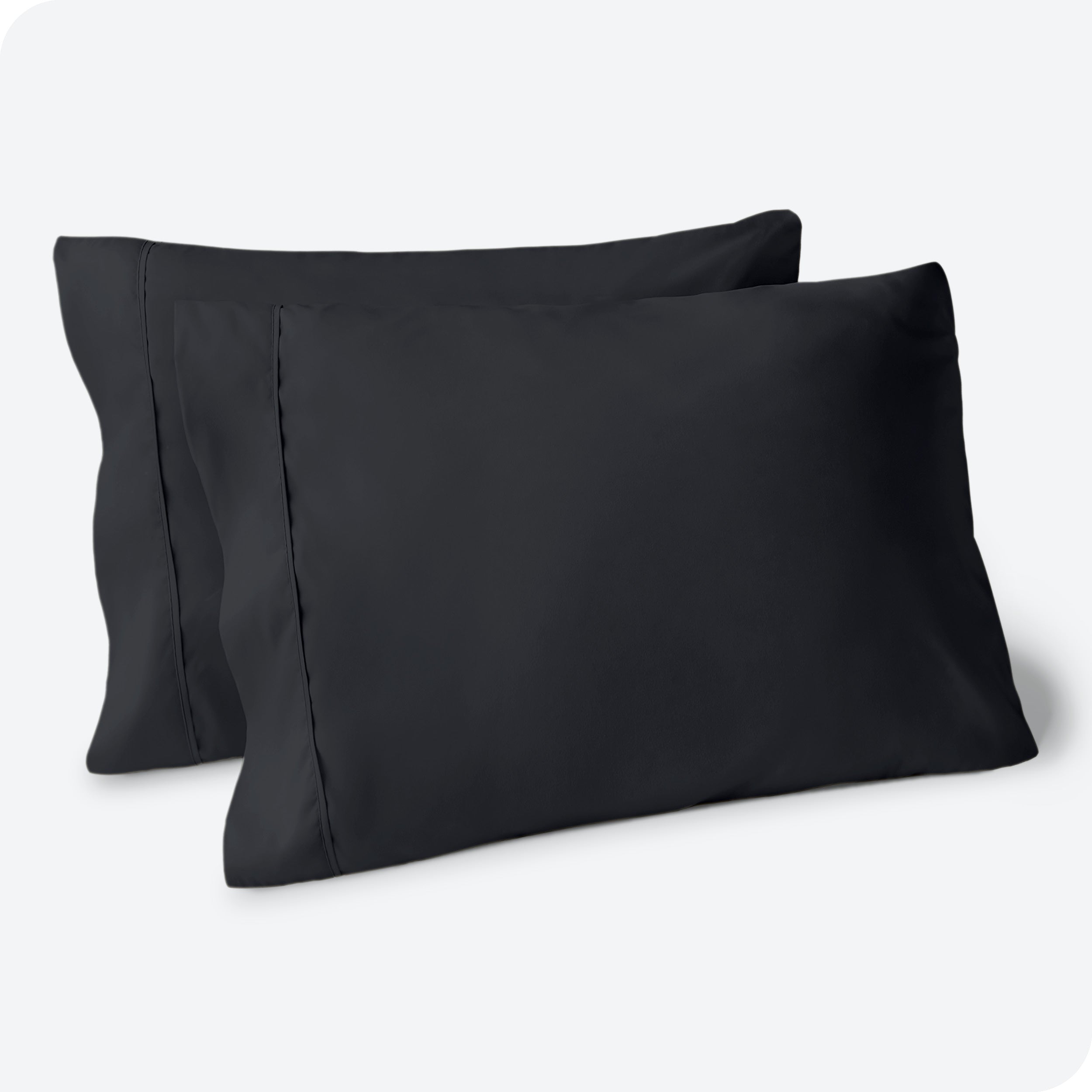 Two pillows on a white background with black pillowcases on them