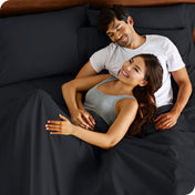 A couple is relaxing in bed with pillows behind them