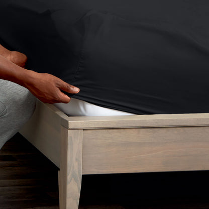 Person adjusting a fitted sheet on a mattress