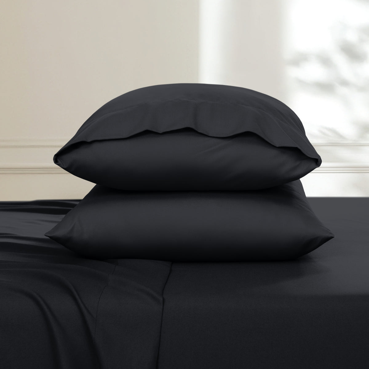 Two pillows stacked on a bed with a neutral background