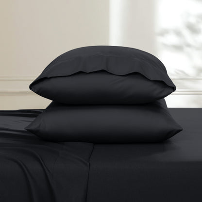 Two pillows stacked on a bed with a neutral background