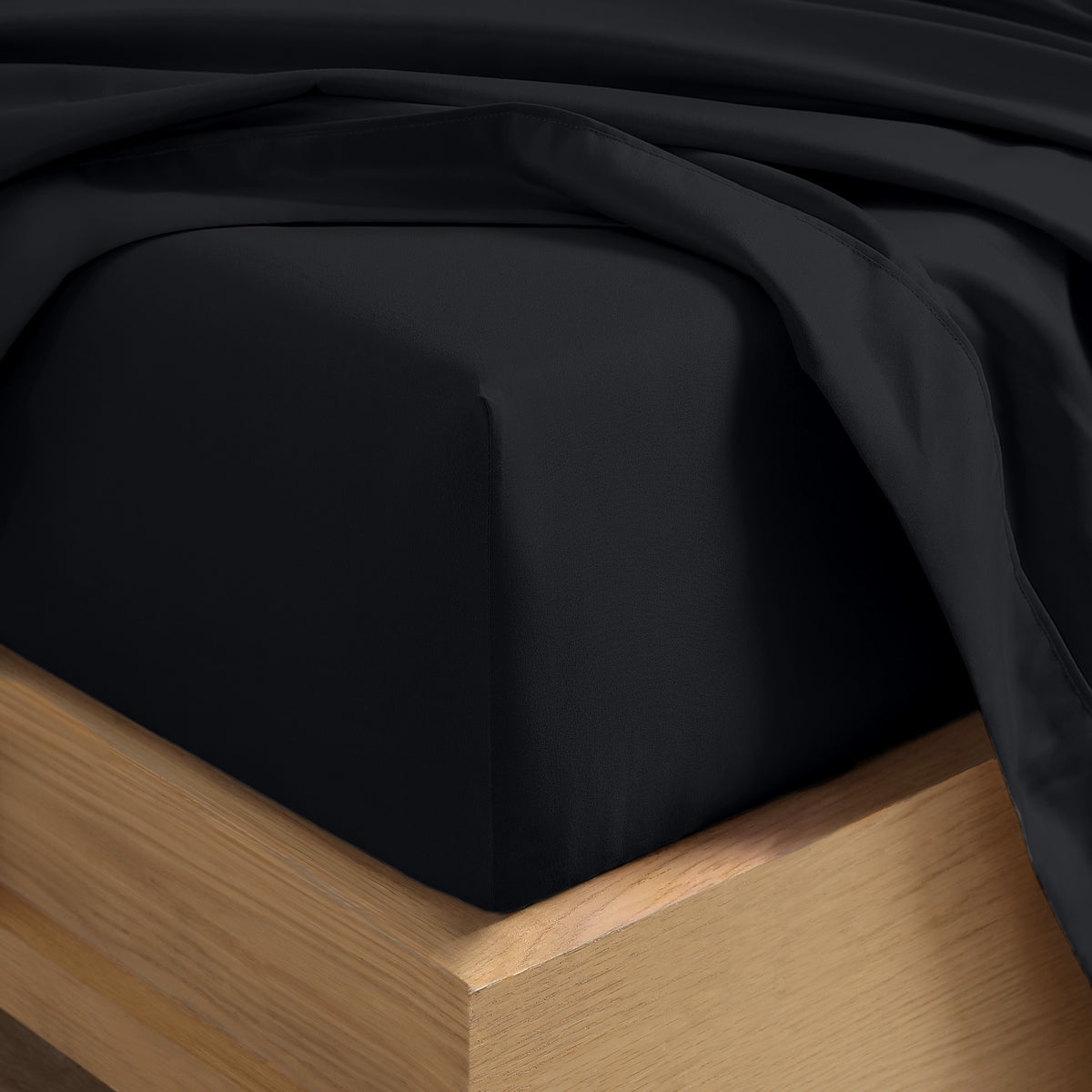 Close up of the corner of a mattress with a fitted sheet and flat sheet on it