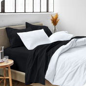 A side view of a bed made with microfiber sheets and a white duvet cover