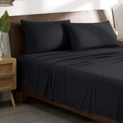 Microfiber stretch bed sheets and pillows on a wooden bed in a bedroom setting.