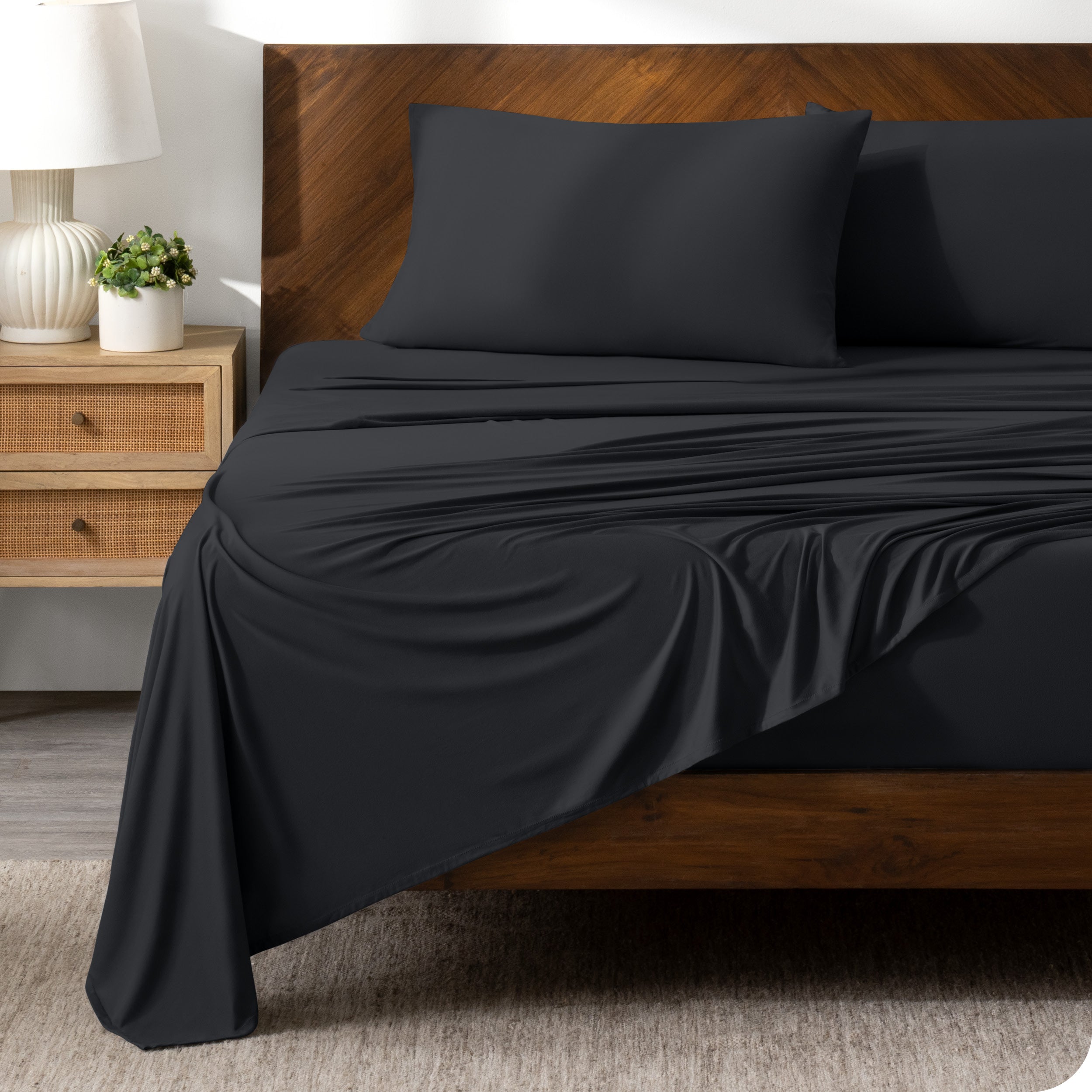 Black sheet set on a bed with a dark wooden bed frame