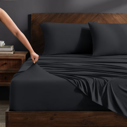 Person adjusting stretch sheets on a bed with a wooden headboard.