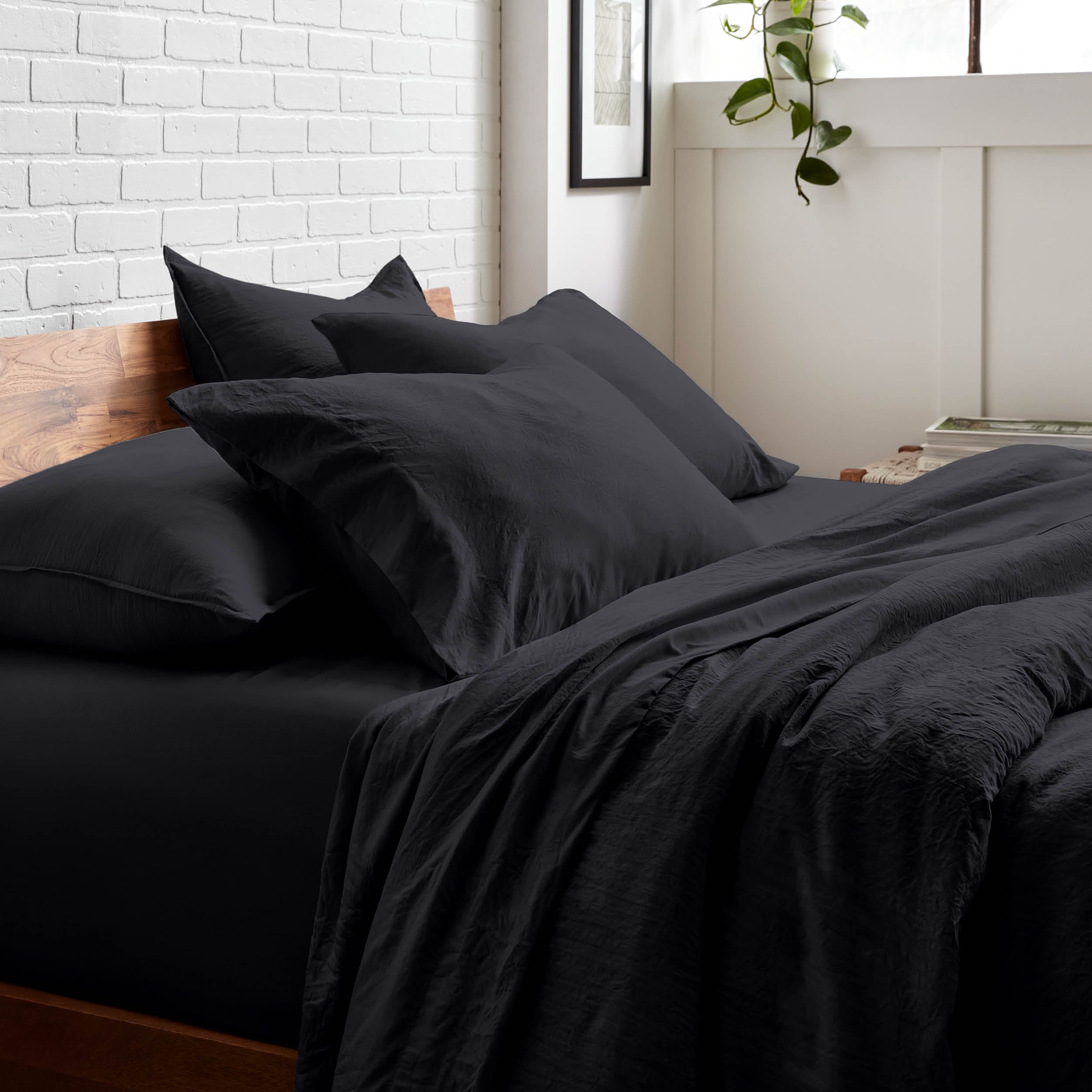 Bedding set on a bed with a white brick wall and window in the background