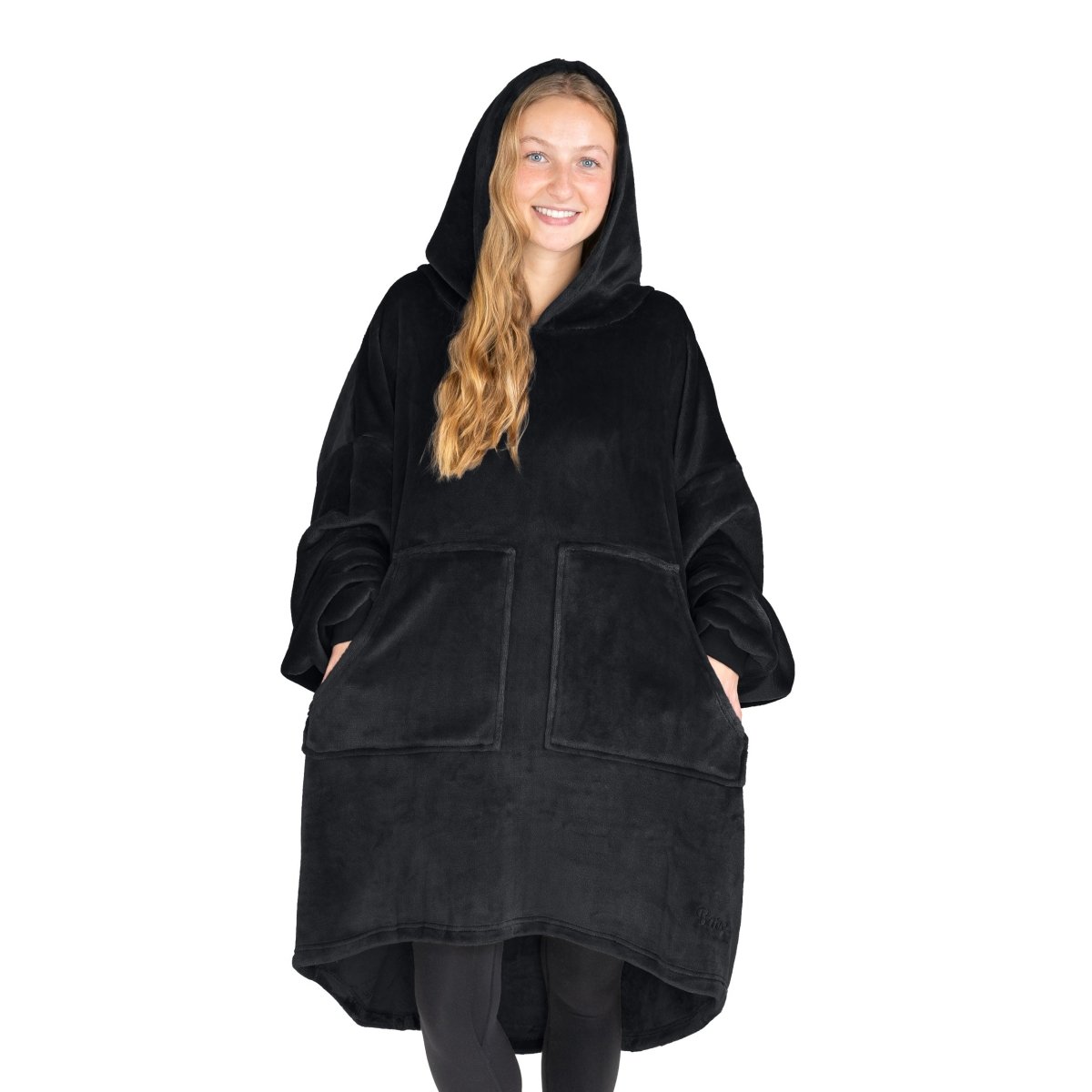 An adult is standing while wearing a microplush wearable blanket