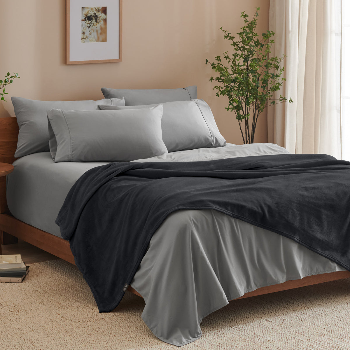 A bed made with grey sheets and a microplush blanket