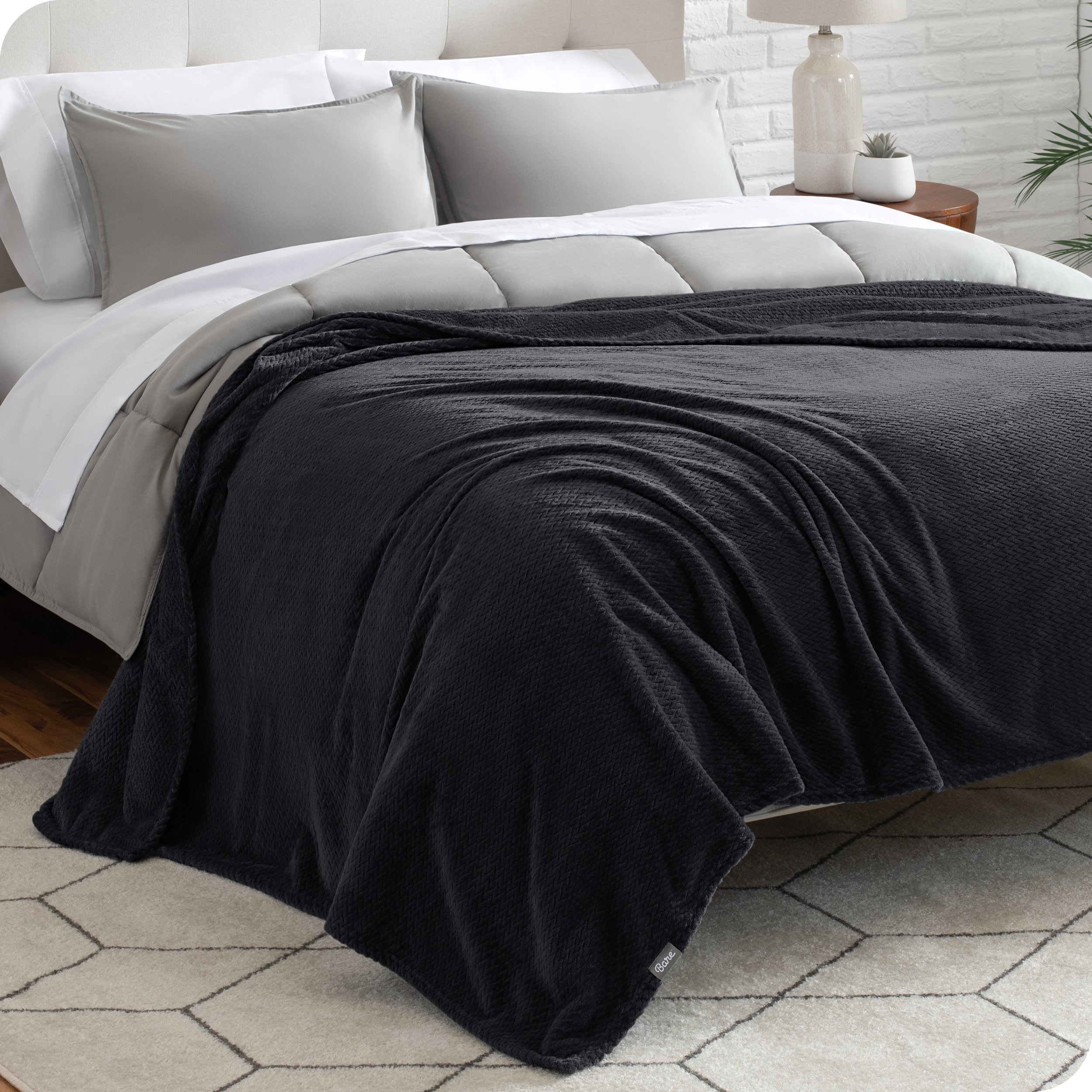 A textured microplush blanket is covering a bed, which has a comforter set on it.
