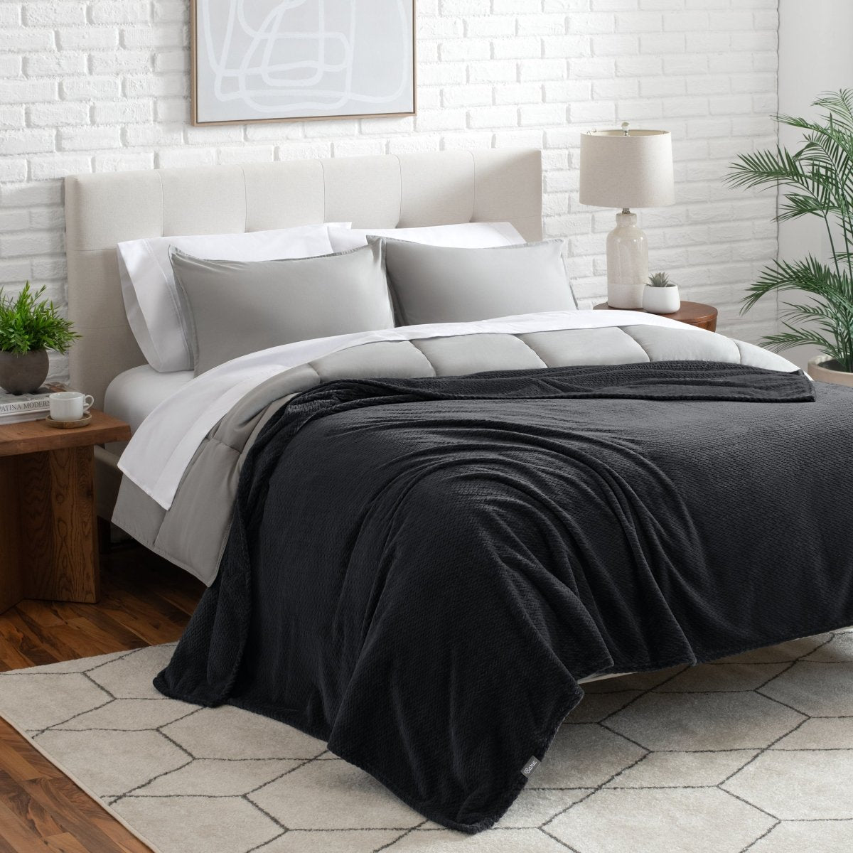 Neatly made bed with a blanket draped over the end of the bed
