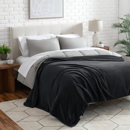 Neatly made bed with a blanket draped over the end of the bed