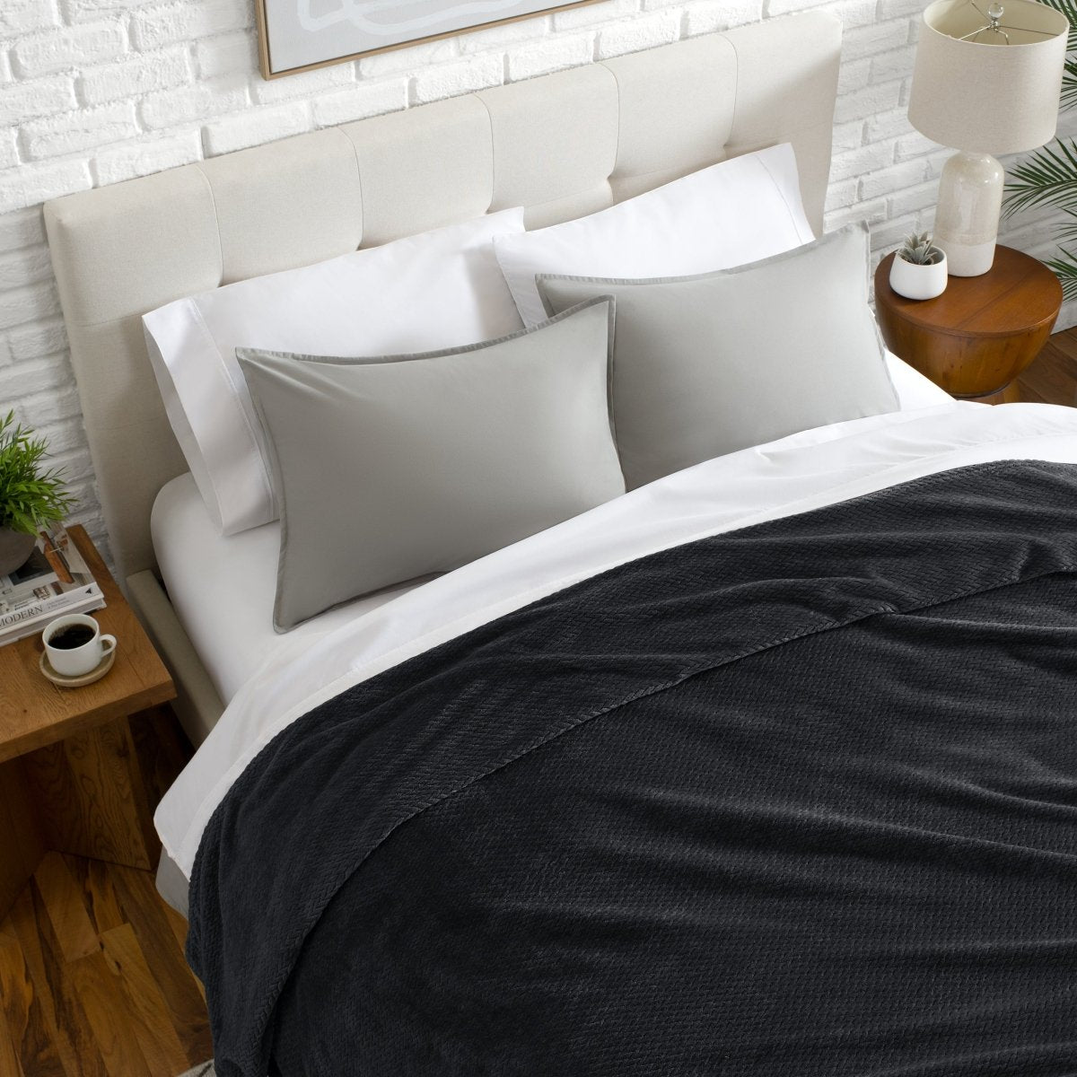 Neatly made bed with a chevron blanket over the comforter
