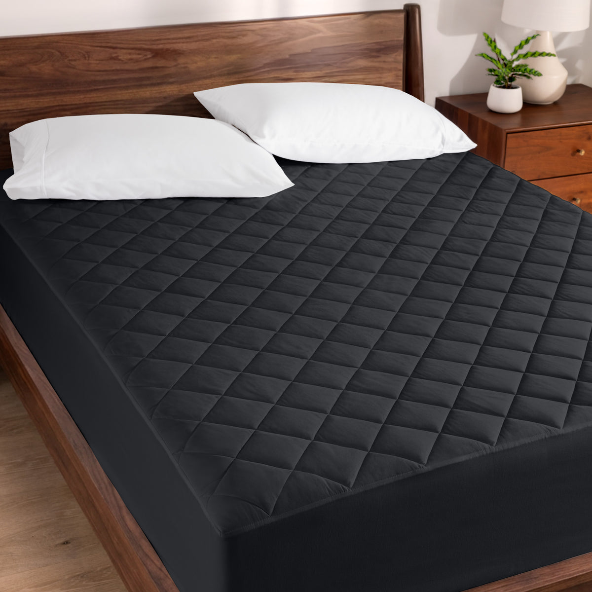 Quilted mattress pad on a bed with wooden headboard and nightstand.