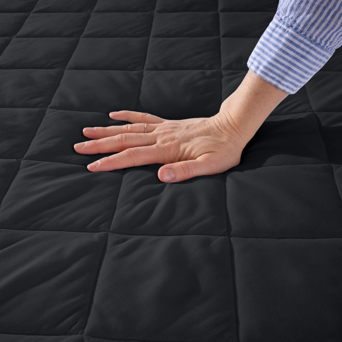 Hand touching a quilted mattress pad.