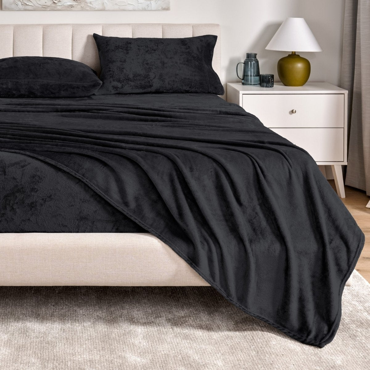 Microplush sheet set on a bed in a bedroom setting with a nightstand and lamp.