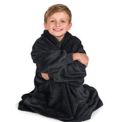 A boy is sitting while in a microplush wearable blanket.