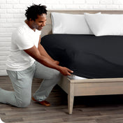 Man putting the corner of fitted sheet on a mattress