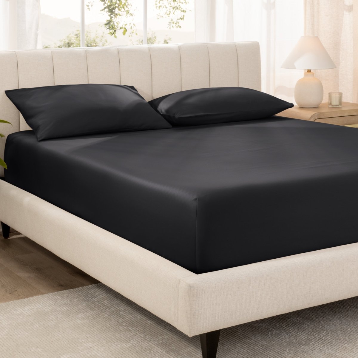 Bed with fitted sheet and pillowcases in a bright room.