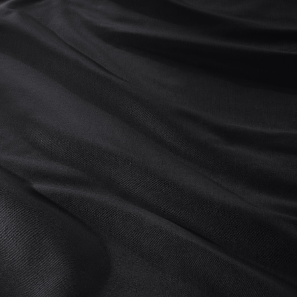 A close-up of draped sateen fabric with soft folds and a smooth texture.