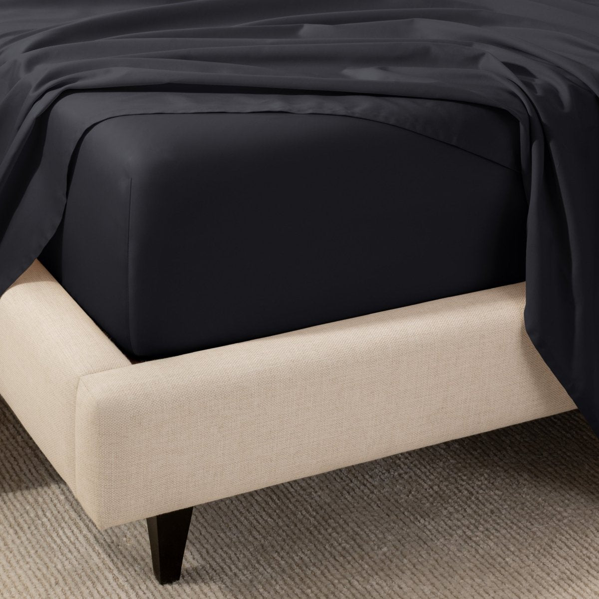 A close-up of the corner of a bed with a fitted sheet and matching flat sheet.