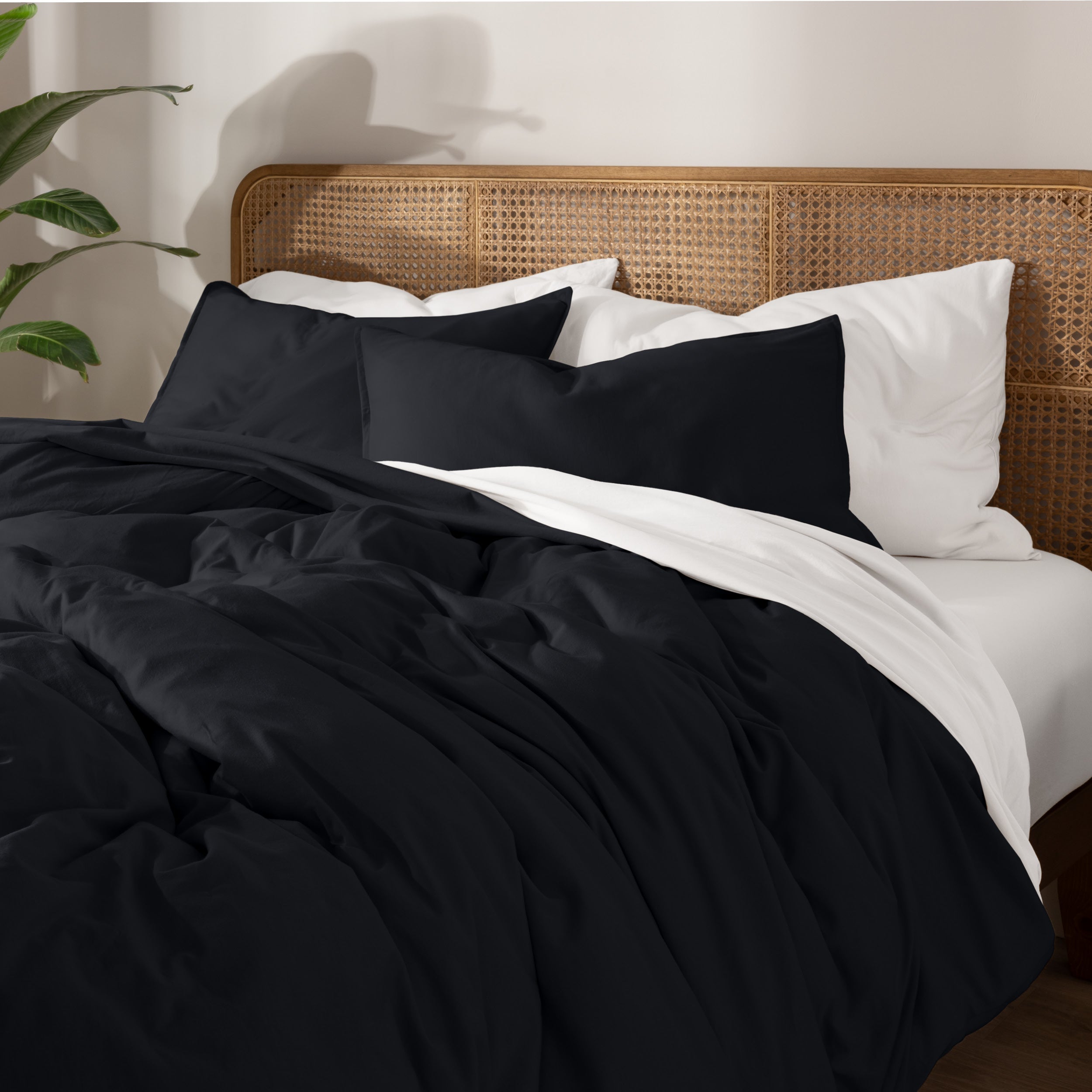 Bedding set on a bed with a wicker nightstand and lamp in a bedroom setting.