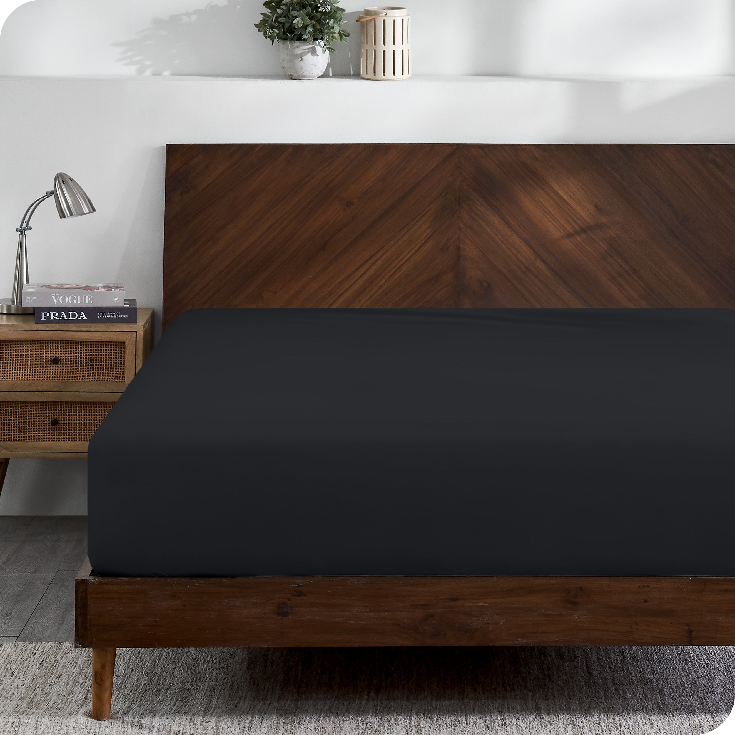 A modern wooden bed frame with a fitted sheet on the mattress