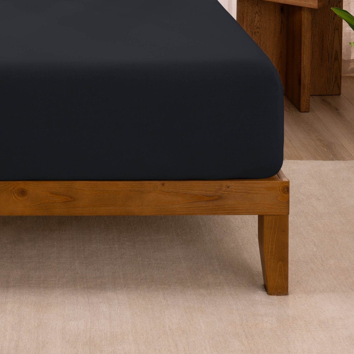 Fitted sheet on a wooden bed frame with a neutral background
