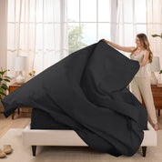 Woman putting a sheet set on a bed in a bright bedroom.