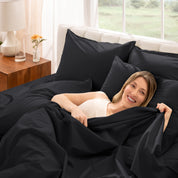 Woman lying in bed with percale bedding in a bright bedroom