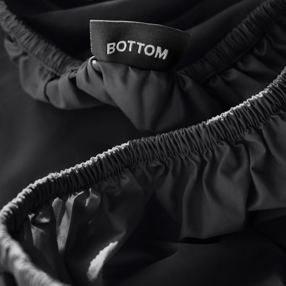 Close-up of a fitted sheet with a black fabric brand label reading BOTTOM.