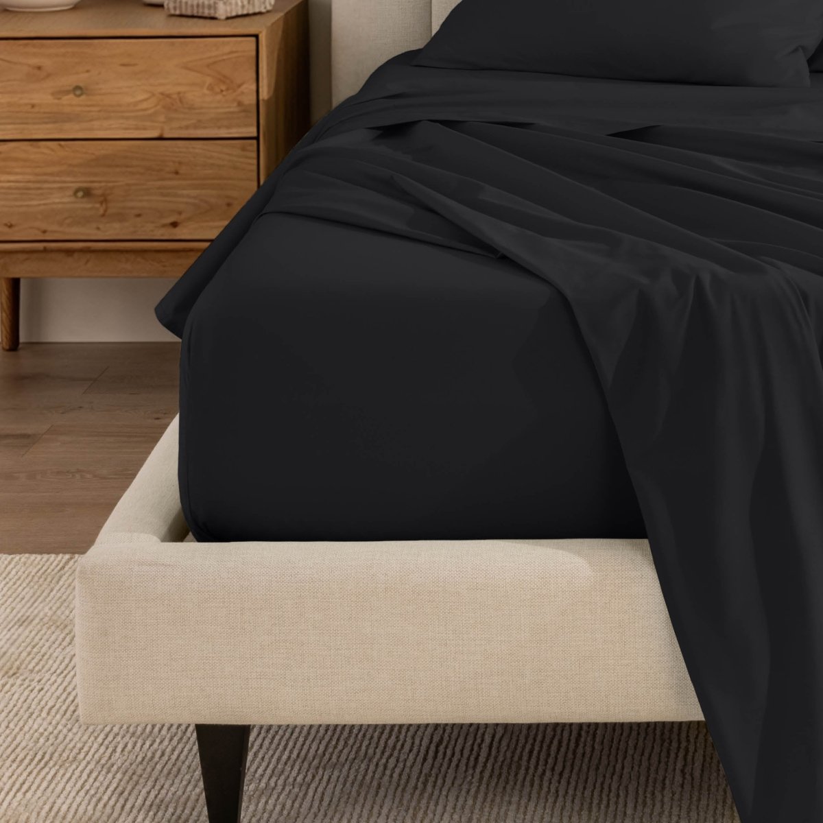 Top sheet and a matching fitted sheet on a bed with a beige bed frame
