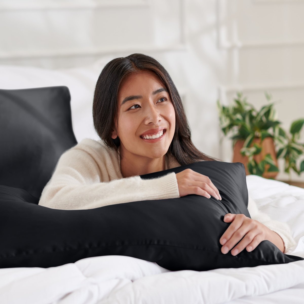 Woman lying on a bed with a body pillow, smiling.