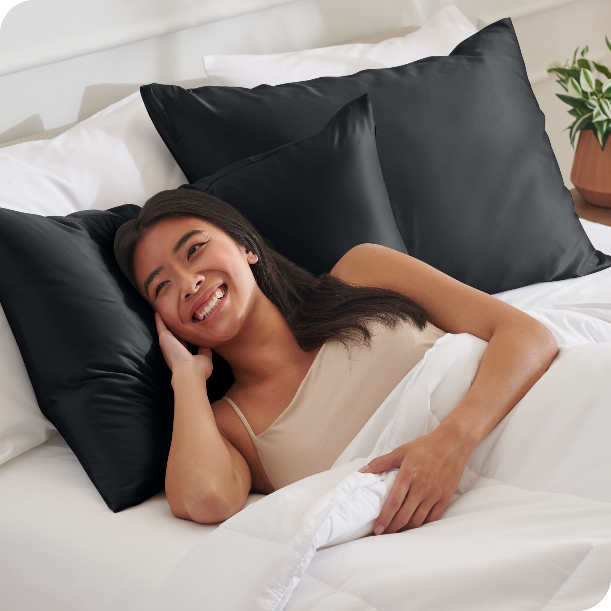 A woman is in bed and resting her head on a satin pillowcase