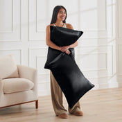 Woman holding 2 pillows with satin pillowcases on them