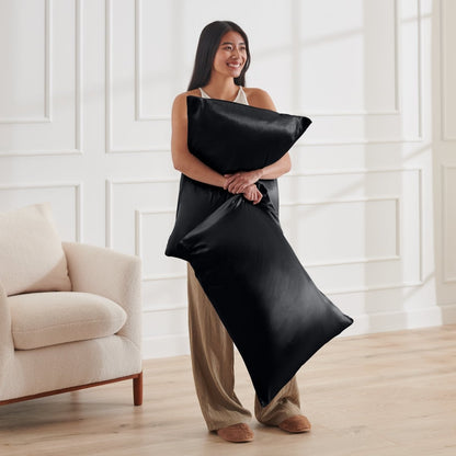 Woman holding 2 pillows with satin pillowcases on them