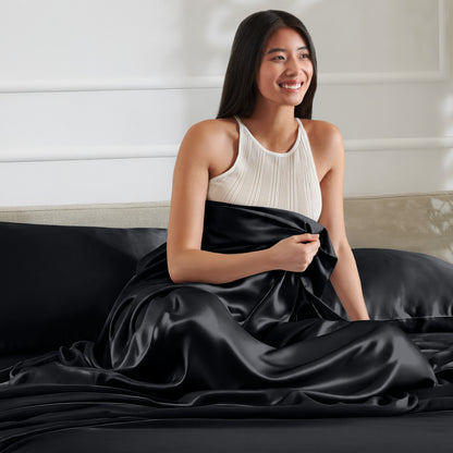 Woman sitting on a bed with satin sheets