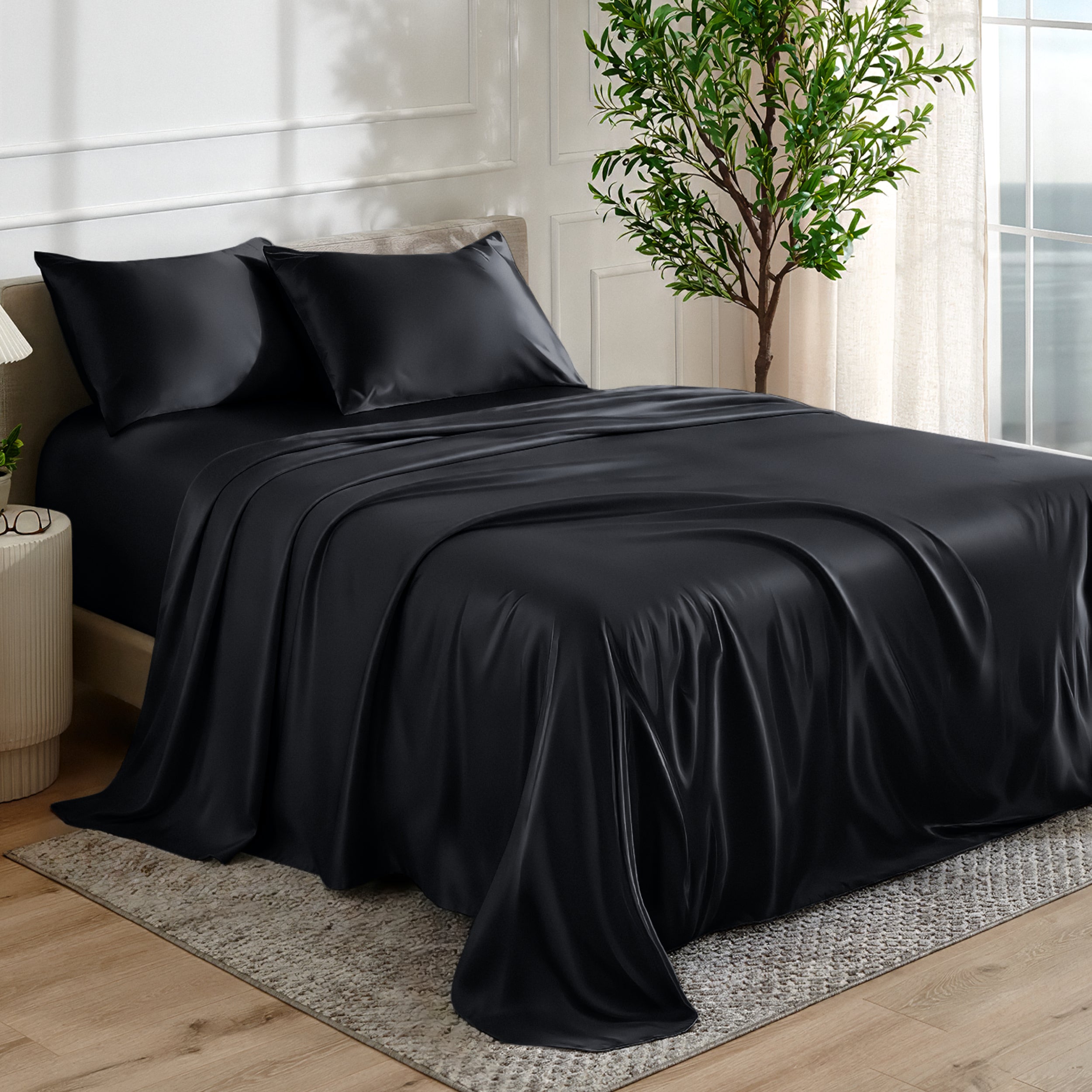Satin sheet set on a bed in a bedroom with a plant and window in the background.