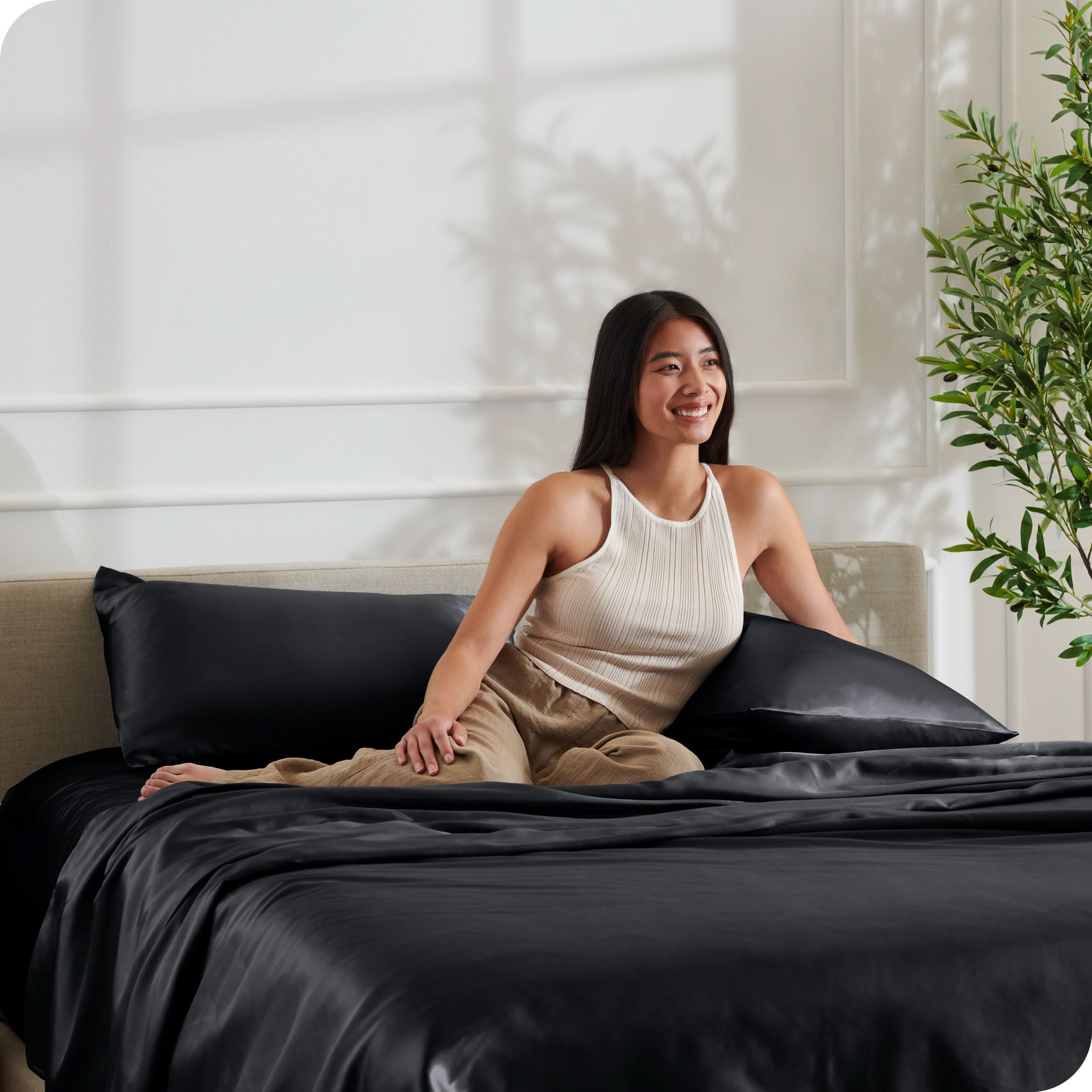 A woman is resting on a bed make with satin sheets