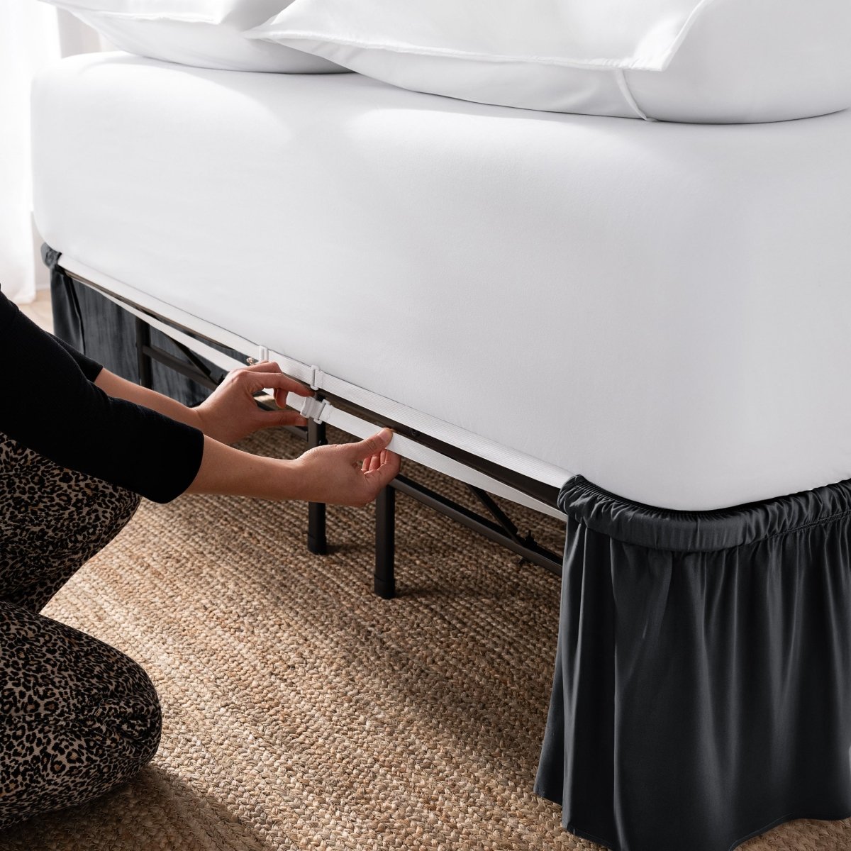 Adjustable bed skirt on a bed showing the elastic strap.