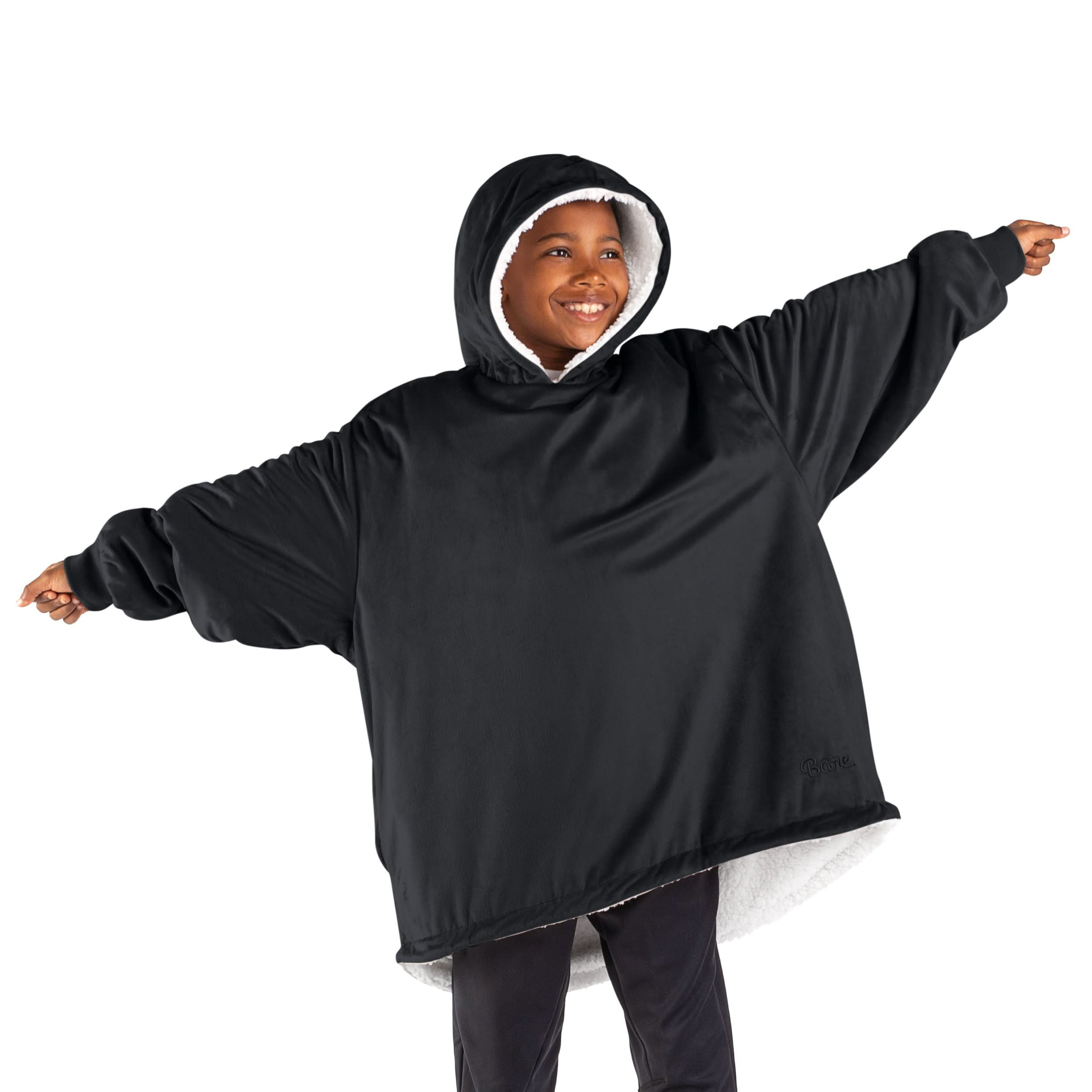 A boy standing with his arms stretched out while wearing a wearable blanket