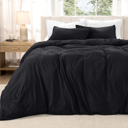 Washed duvet set on a bed in a bright bedroom with a lamp and window.