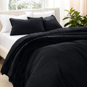 Washed bedding set on a bed in a bedroom with plants and nightstands.