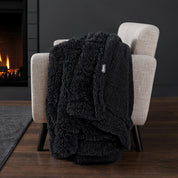 Sherpa blanket draped over an armchair in front of a fireplace.
