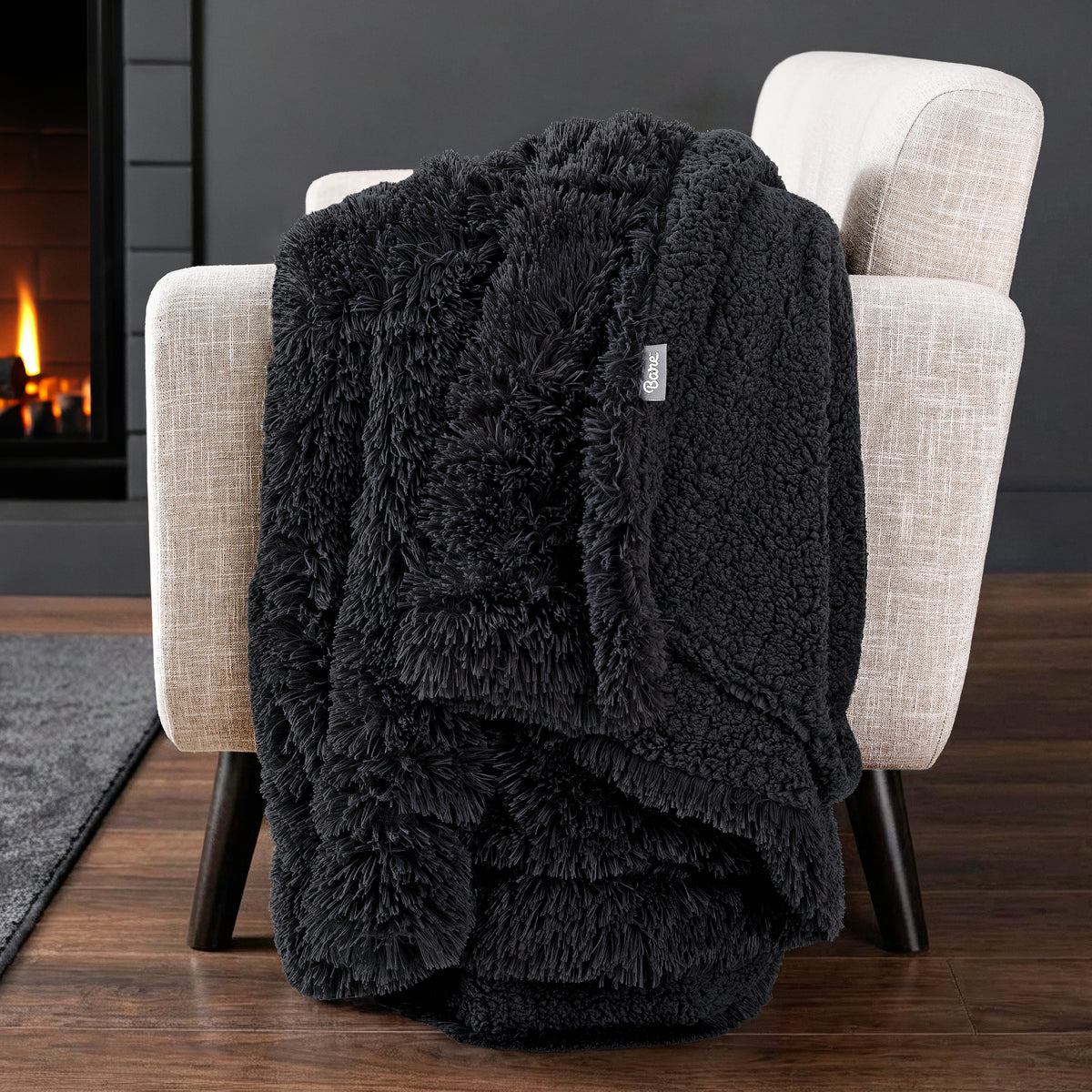 Sherpa blanket draped over an armchair in front of a fireplace.